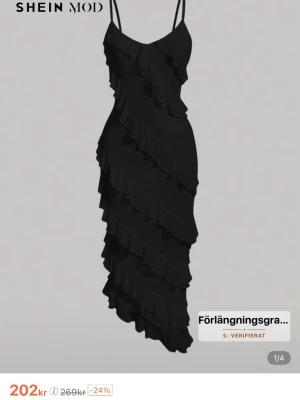 Svart volangklänning från SHEIN - Snygg svart klänning med smala axelband och asymmetriska volanger som ger en cool och trendig look. Klänningen har en figurnära passform och är tillverkad i ett lätt syntetmaterial. Perfekt för dig som gillar att sticka ut med detaljer! Oanvänd!