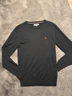Svart tröja från US Polo Assn - Svart US Polo crewneck, köpt nyligen knappt använd. Storlek S sitter bra i midja och armar lite stor i kragen annars allmänt bra passform