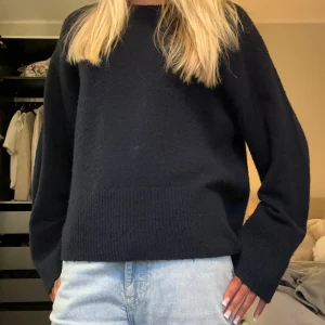 Mörkblå stickad tröja med lång ärm - Snygg mörkblå stickad tröja med rund hals och långa ärmar. Modellen är loose fit och har bred ribbad kant vid nederdelen och ärmsluten. Perfekt att matcha med jeans för en chill look.