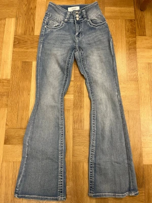 Bootcut jeans med fina fickor - Bootcut jeans i ljusblå tvätt från H&Y med tre dekorativa knappar framtill🩷. Midwaist men om man vill ha lowwaist går dem nog lätt att sy om, jag kan inte sy och därför säljer jag😚. Snygga kontrastsömmar och pärlbroderade bakfickor med glittriga detaljer. Klassisk femficksmodell i mjukt denimtyg. Köpta i usa 🇺🇸 