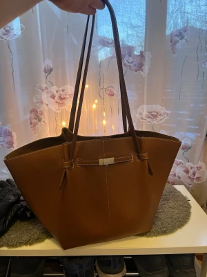 Brun axelväska - Säljer en stor brun axelväska i skinnimitation med långa handtag. Använd en gång. Uttagbar innerficka. Myxket rymlig