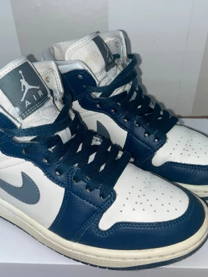 Nike Air Jordan 1 Mid blå/vit EUR 36 - Nike Air Jordan 1 Mid sneakers i marinblått och vitt med ljusblå swoosh. Originalpris: 1700kr.