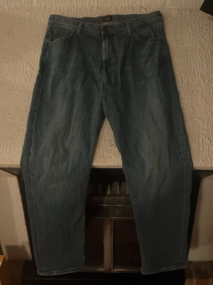 Lee jeans WEST W33 L32 blå - Säljer ett par klassiska blå jeans från Lee, modell WEST. Jeansen har fem fickor, Lee-lapp i skinn på bakfickan och snygga kontrastsömmar. Passar dig som gillar en tidlös look och vill ha ett par jeans med normal passform.