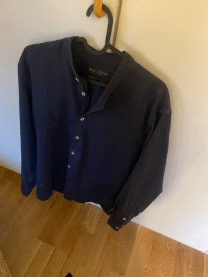 Skjorta - Säljer en mörkblå skjorta från Marc O'Polo i storlek M. Skjortan är långärmad och har en clean, stilren look som funkar till många olika outfits. Jag är 176 samt ganska smal och tycker att den är för stor.