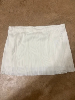 Vit kortkjol från SHEIN - Säljer en vit kortkjol från SHEIN i storlek S. Kjolen har ett snyggt ribbat mönster och elastisk midja för skön passform. Perfekt till sommaren och enkel att matcha med olika toppar. Ganska kort 