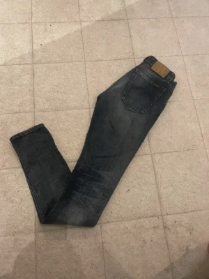 Mörkblå jeans från Nudie - Snygga mörkblå jeans från Nudie med klassisk femficksdesign och läderpatch bak i midjan. Jeansen har en smal passform och är tillverkade i mjukt jeansmaterial som sitter skönt hela dagen.
