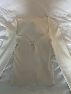 Vit långärmad topp från H&M XS - Säljer en vit långärmad topp från H&M i ribbad stretchig kvalitet. Toppen har en snygg v-ringning med cut-out och en stor pärlformad dekoration framtill. Tröjan är köpt av en annan användare på plick och då använd 2 ggr. Jag har använt den 1 gång, skriv om du har frågor eller för fler bilder💞💞