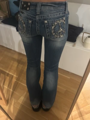 Miss me jeans med broderade fickor - Blå lågmidjade miss me jeans. Baksidan har två fickor med broderade peace-symboler och nitar.