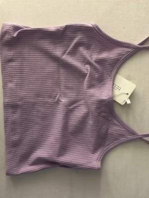 Ljuslila ribbad linnetopp - Säljer en ljuslila ribbad linnetopp. Aldrig använd och har prislapp kvar. 