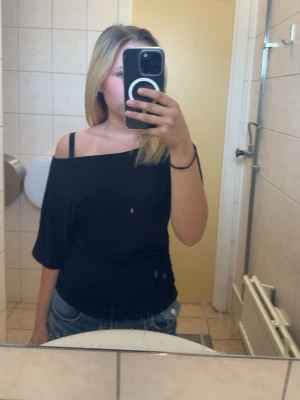 Svart offshoulder topp - Säljer en svart offshoulder topp med trekvartsärm i storlek xs . Toppen har en lös passform upptill och sitter lite tajtare vid midjan. Perfekt för dig som gillar en stilren och enkel look med en twist.