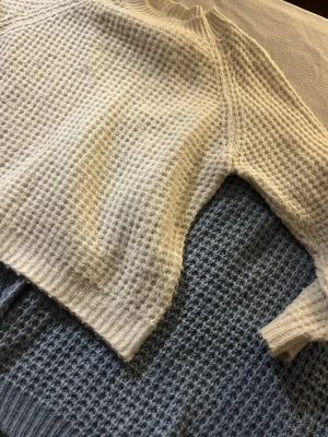 Stickad tröja i vitt och blått - Två stickade tröjor med grov struktur, en i vitt och en i blått. Båda har ribbad krage, ärmslut och nederkant. Perfekt för lager-på-lager och chill höst- eller vinterstil. Snyggt avslappnad passform och mjukt material. 50 kr styck❗️😍