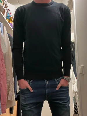 Svart långärmad tröja från Indicode - Svart långärmad tröja från Indicode med rund hals och ribbade muddar. Enkel och stilren design som passar perfekt till jeans eller chinos. Materialet är mjukt och känns skönt mot huden, perfekt för kyligare dagar.