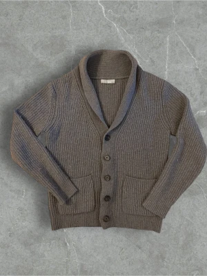 Grå ribbstickad kofta med sjalkrage - Mysig grå kofta med ribbstickat mönster, sjalkrage och fem knappar framtill. Två stora fickor framtill ger en chill vibe. Perfekt att slänga på sig när det är lite kyligt ute. Materialet känns mjukt och tjockt, troligen ullblandning.