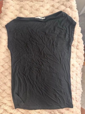 Svart basic t-shirt från 157 - En enkel svart t-shirt från 157 med rund hals och korta ärmar. Tillverkad i mjuk bomull som känns skön mot huden. Perfekt att matcha med jeans eller shorts för en clean och avslappnad look.