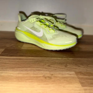 Nike Air Zoom sneakers i ljusgul mesh - Använda vid en gympass inomhus. Snygga Nike sneakers i ljusgul mesh med vita detaljer och snörning. Skorna har en sportig design med platt sula och ventilerande material, perfekt för dig som gillar en fräsch och modern look. Ikonisk Nike-logga på sidan och bekväm passform.