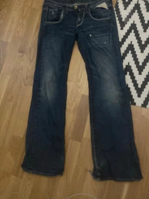 Mörkblå jeans från Replay - Snygga mörkblå jeans från Replay med bootcut/straight passform( dem är INTE skinny)Jeansen har slitningar och en lätt tvättad look som ger en avslappnad vibe. Tillverkade i robust denim som passar perfekt till en streetwear-stil.