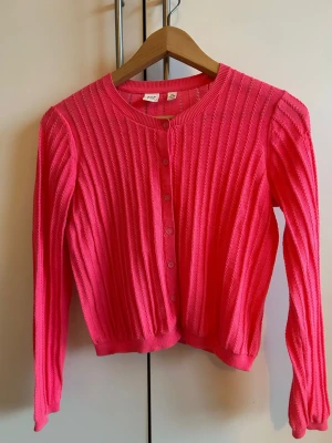 GAP Bright Pink Cardigan 💖✨ - Superfin färgklick från GAP Kids! En klarrosa kofta i mjuk kvalitet med jättesöta pointelle-detaljer (hålmönster) och klassiska knappar. • Storlek: 13–14 år (ca 160 cl) – funkar även som en XS för vuxna! • Mått: Axel 35 cm, längd 45 cm. • Skick: Jättefint skick och supermjuk! ☁️ Perfekt att liva upp outfiten med! 🌸 