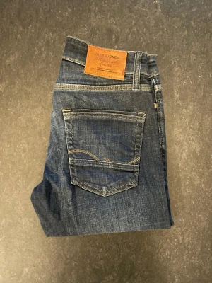 Jack & Jones jeans (mike comfort) - Säljer ett par marinblåa Jack&Jones jeans med snygg tvätt, storlek 28/32, straight fit. Mycket bekväma jeans och är lite stretchiga. Mycket fint skick där de har använts fåtal gånger.                                Nypris 900kr                                                    Mått: A=36cm B=73cm C=99cm D=16cm      Fråga gärna om fler bilder eller om det är något ni generellt undrar!                                                     Checka in profilen för liknande jeans!