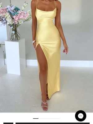 Gul långklänning med slits - Perfekt för Bal! Elegant gul långklänning i satin med smala axelband och öppen rygg med snörning. Endast provad en gång då jag valde en annan färg! Prislapp kvar, perfekt för balklänning !!🤩💓