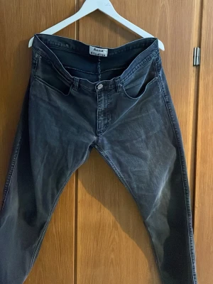 Svarta Acne Studios jeans - Säljer ett par svarta jeans från Acne Studios med klassisk femficksmodell och raka ben. Jeansen har en snygg tvättad look och silverfärgade knappar. Perfekta för dig som gillar stilrena och tidlösa plagg.