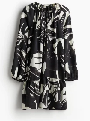 Svartvit mönstrad klänning från H&M - Svartvit långärmad klänning från H&M med abstrakt mönster. Klänningen har v-ringning med knytband och är tillverkad i 89% LENZING™ ECOVERO™ viskos. Perfekt för dig som gillar unika prints och sköna material. Armarna har en knapp var som går att öppna. 