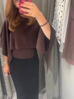 Brun poncho tröja  från Zara - Snygg brun blus från Zara med volangdetaljer och vida, trekvartsärmar. Tillverkad i mjukt, stretchigt material.