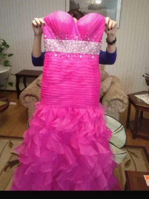 Chockrosa långklänning från Partytime - Säljer en chockrosa långklänning från Partytime med strapless sweetheart-ringning och glittriga paljettdetaljer över bysten. Kjolen har volanglager i tyll för extra volym och dramatisk känsla. Tillverkad i polyester och stängs med dragkedja bak. , storlek XS .       använd endast en gång och är kemtvättad, pytteliten hål nerifrån, se bild. Trots kemtvätten så finns det några små  fläckar nerifrån kvar men påverkar inte alls utseendet på klänningen.