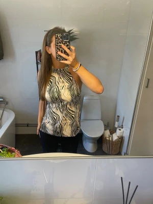 Zebramönstrad halterneck topp - Snygg zebramönstrad halterneck topp med öppen rygg och knyt i ryggen. Toppen är ärmlös och har svartvita ränder i ett coolt mönster. Ny utan prislapp🤍
