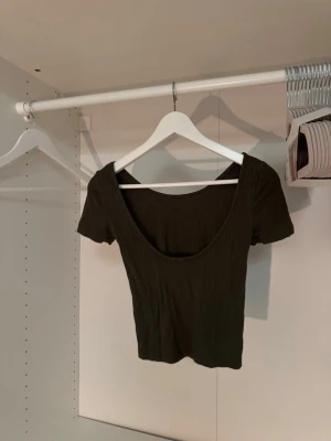 Militärgrön ribbad croppad topp - Snygg militärgrön t-shirt med ribbad struktur och rundad urringning både fram och bak. Öppen rygg🤩 Sitter tight och passar perfekt till höga jeans eller kjol. Enkel men trendig design som är lätt att matcha. Står ej storlek men uppskattar XS-S