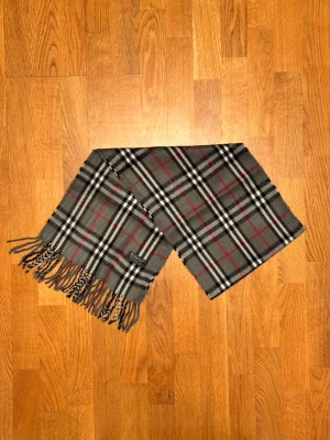 Grå Burberry halsduk - Säljer en grå halsduk från Burberry. Halsduken är i gott skick och är gjord i 100% lamull. Var inte rädd för några frågor. Pris diskuteras inte!