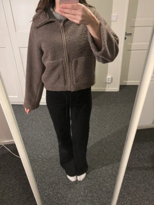 Brun teddyjacka från 157 - Mysig brun teddyjacka från 157 med dragkedja framtill och två fickor. Jackan har en avslappnad passform och är perfekt för kyliga dagar. Tillverkad i mjukt teddy-material som håller dig varm och bekväm.