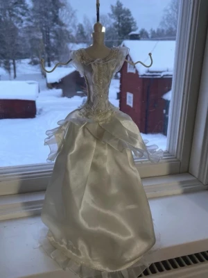Mannequin smyckes hållare - Elegant smyckeshållare i form av en brudklänning i vit satin och spets med pärldetaljer. Klänningen har volangdetaljer och puffiga axlar. Perfekt för att hänga halsband, armband eller ringar på. Några krokar har gått av och några små små fläckar🫰