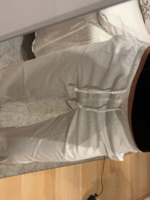 Vita linnebyxor med snörning - Säljer ett par vita linnebyxor med avslappnad passform och snörning i midjan. Byxorna har raka ben.