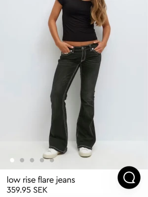 Svarta low rise flare jeans - Snygga svarta low rise jeans med flare-ben och kontrastsömmar. Jeansen har vita dekorativa sömmar längs benen och bakfickorna.I storlek 158 och är helt oanvända utan prislapp