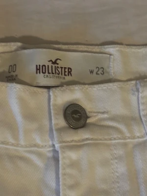 Vita  shorts från Hollister - Säljer ett par vita shorts från Hollister med slitna detaljer och fransig kant. Klassisk femficksmodell med knapp och dragkedja framtill. Perfekta för sommaren och riktigt snygga till crop tops eller t-shirts. Aldrig andvänt