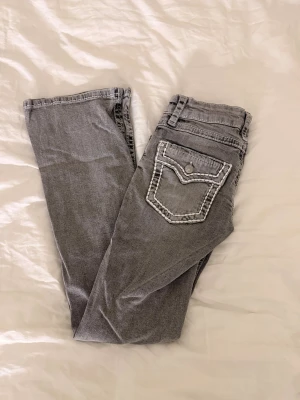 Grå jeans från Gina - Säljer ett par grå jeans från Gina Tricot i storlek 152. Byxorna har en snygg bakficka med vit kontrastsöm och knapp. Materialet är jeans med tydliga sömmar som ger en cool look. (Pris kan diskuteras)