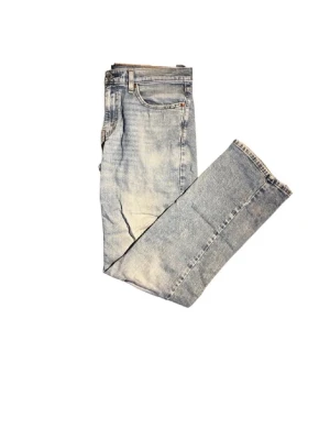 Levi's 514 ljusa jeans straight fit - Säljer ett par Levi's 514 jeans i ljusblå tvätt med klassisk straight fit. Jeansen har fem fickor, Levi's patch bak och röda Levi's-tag på fickan. Materialet är slitstarkt denim och benen har några slitningar. 