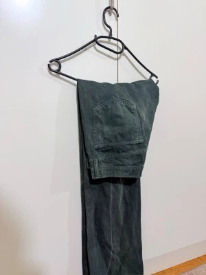 Svarta cargopants från Hope - Säljer ett par svarta cargopants från Hope med stora fickor på benen och klassisk rak passform. Byxorna är gjorda i slitstark bomull och har en cool, urban vibe. Perfekta för dig som gillar streetstyle och funktionella detaljer.