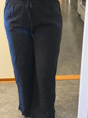 Svarta linnebyxor med snörning - Säljer ett par svarta linnebyxor med avslappnad passform och snörning i midjan. Byxorna har raka ben och elastisk midja för extra komfort. Perfekta för chill dagar och enkla att matcha med sneakers eller sandaler.