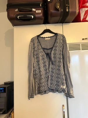 Mönstrad blå-vit kofta Odd Molly - Säljer en snygg kofta från Odd Molly. Koftan är blå och vit med ett detaljerat geometriskt mönster, v-ringad hals och knytband framtill. Långärmad med fina kanter och mjukt stickat material som känns skönt mot huden. Storlek 2 som enligt deras storleksguide motsvarar en M. Mycket fint skick, jag hittar inga synliga anmärkningar eller defekter.  