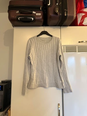 Ljusgrå stickad tröja med kabelmönster - Säljer en ljusgrå stickad tröja med klassiskt kabelmönster. Tröjan har rund halsringning, långa ärmar och ribbade muddar vid ärmslut och nederkant. Perfekt för dig som gillar enkel och stilren design. Från märket Odd Molly. Storlekslappen saknas men jag tror det är en 2 som enligt deras storleksguide motsvarar en storlek M. Mer använd men fortfarande fint skick, 