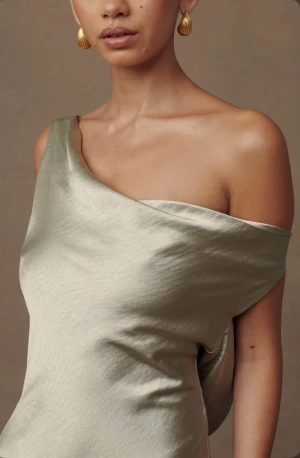 Elegant långklänning  - Elegant långklänning med asymmetrisk design och vacker lyster. En axel fri framtill och öppen rygg med dekorativa band ger en sofistikerad look. Storlek XXS, helt ny, beige/grön färg, köpt för 800kr. Säljer då klänningen var för lång. Perfekt till fest, bröllop eller gala.