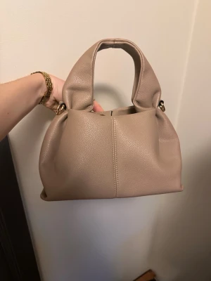 Beige/Taupe handväska  - Använd fåtal gånger. Axelband medföljer, se bild. Köpt i en butik i Nice. 