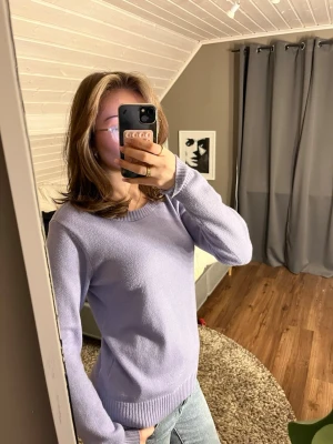 Ljuslila stickad tröja med rund hals - Säljer en ljuslila stickad tröja med rundad hals och ribbade muddar vid ärmslut och nederkant. Tröjan har en enkel och clean look, perfekt att matcha med jeans eller kjol. Långärmad och mjuk i materialet, passar dig som gillar stilrena plagg.