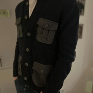 Gran Sasso cardigan - Snygg marinblå kofta med stora grå fickor och knappar framtill. Den har långa ärmar och är perfekt för en stilren look. Passar bra till jeans för en avslappnad stil.