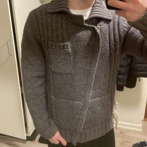 Grå unik stickad cardigan - Otroligt fet unik grå stickad cardigan. Modellen är 180cm, 73kg. Priset kan såklart diskuteras