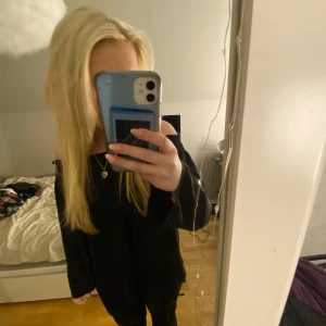 Svart off-shoulder topp - Snygg svart off-shoulder topp med smockdetaljer vid halsringningen. Perfekt för en stilren look. Toppen har långa ärmar och en lös passform. 42 men sitter som 36