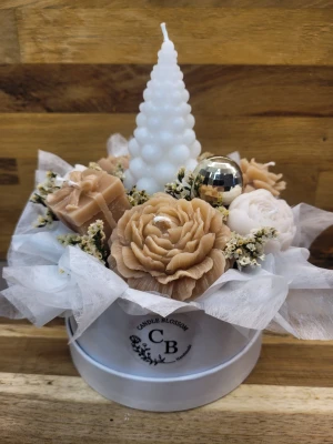 Ljus bukett box Jul - Unikt ljusarrangemang med handgjorda ljus i form av beige och vita blommor samt ett vitt bubbligt konformat ljus. Arrangemanget är dekorerat med torkade blommor och en silverfärgad kula, allt placerat i en vit rund ask med logotyp. Perfekt som present eller dekoration.
