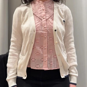 Söt Teenie Weenie-kofta i krämvitt - Söt Teenie Weenie-kofta i krämvitt, stl M (165/88A) Charmig och mjuk kofta i preppy stil med broderad björnlogga. V-ringning och knäppning fram, passar perfekt till vardag eller skola. I mycket gott skick. Material: 82,6 % bomull, 17,4 % akryl. Mått: axel 36 cm, ärm 64 cm, längd 62 cm. Hämtas i Kista eller skickas.