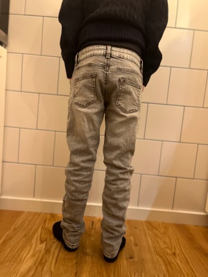Grå jeans med smal passform - Snygga grå jeans med tvättad look och klassiska fem fickor. Byxorna har smal passform, normal midja och raka ben. Perfekta för dig som gillar en stilren och enkel vibe. Materialet är jeans och färgen är ljusgrå.